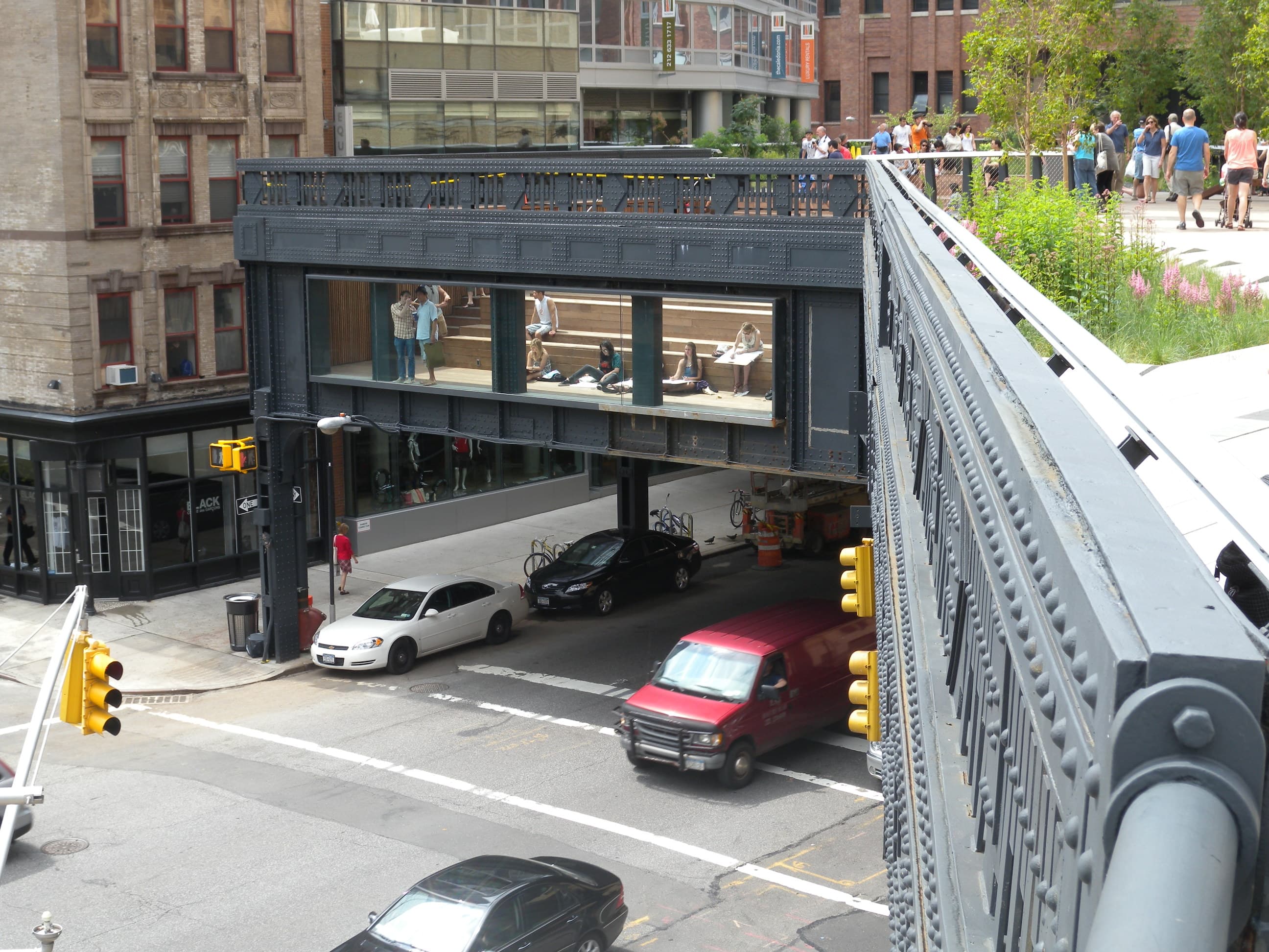 The High Line park after opening — wood-plank pathway threaded through perennial plantings, glass railings, and seating areas.